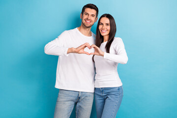 Portrait of two good mood nice cheerful persons dressed white shirts cuddling hands showing heart isolated on blue color background