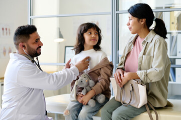 Pediatrician listening to heartbeat of child with stethoscope during medical exam in hospital