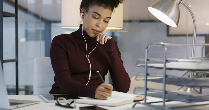 Woman, office and translation with earphones, writing notes or ideas for communication, night and audio at desk. Young african businesswoman, earbuds and information in notebook with language expert