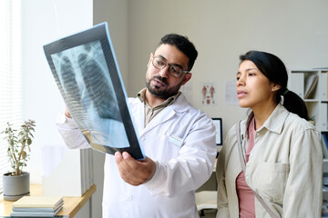 Doctor discussing x-ray image together with patient during her visit to hospital