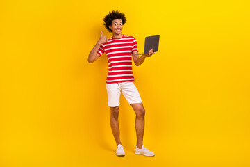 Full length photo of excited cool man dressed red t-shirt thumb up texting modern gadget isolated yellow color background
