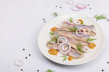 Salted herring with dijon mustard, dill and red onion rings. Marinated filleted fish on light stone