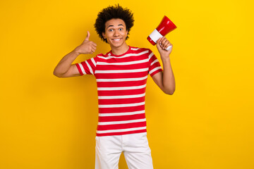 Photo of cheerful cool man dressed red t-shirt rising bullhorn thumb up isolated yellow color...