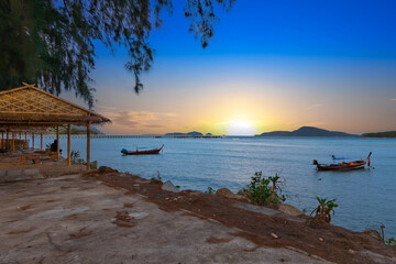 Fototapeta na wymiar Sunset over Rawai Beach in Phuket island Thailand. Lovely turquoise blue waters, lush green mountains colourful skies and beautiful views the pier and long tail boats. Sky is taken seperate from Body 