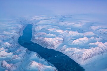 Aerial shot of Greenland mountains and glaciers at sunset.