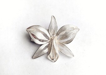 Filigree silver brooch with orchid motif isolated on white background.