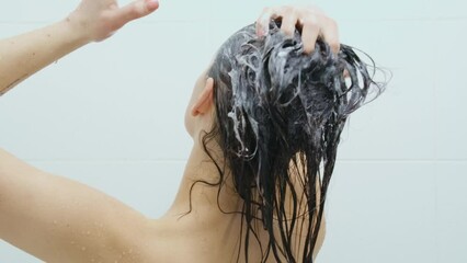 Close up young woman bathing in shower and washing her hair with shampoo on white background in bathroom. Concept of process washing body and brown hair in shower. - Powered by Adobe