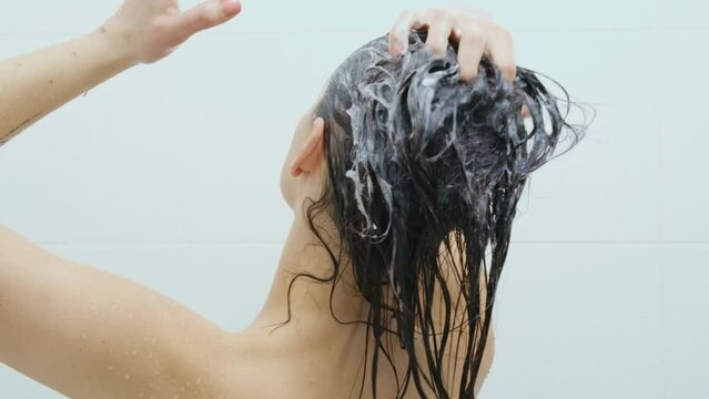 Close Up Young Woman Bathing In Shower And Washing Her Hair With Shampoo On White Background In Bathroom. Concept Of Process Washing Body And Brown Hair In Shower.