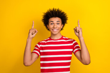 Portrait of positive friendly man beaming smile direct fingers up empty space isolated on yellow color background