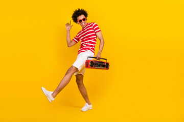 Fototapeta na wymiar Full length photo of cool funky guy dressed red t-shirt dark glasses dancing enjoying boom box songs isolated yellow color background