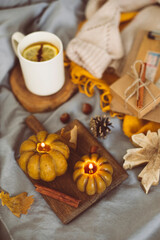 Top view on cozy mood composition with book, pumpkin candles, cup with hot tea and autumn decoration