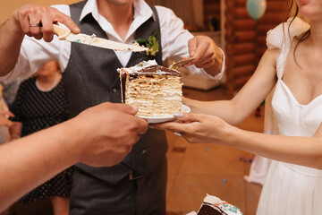 hands of the bride and groom with a knife cut into pieces a wedding holiday cake