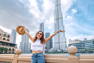 happy traveler girl with outstretched arms, embracing the incredible view of majestic tower in Dubai, UAE