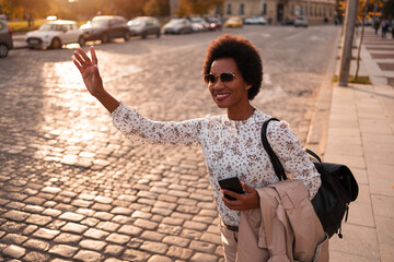 Beautiful woman calling a taxi ride, waving, dressed nicely.