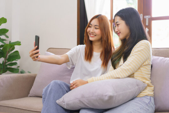 Activity at home concept, LGBT lesbian couple smiling and using smartphone to selfie together