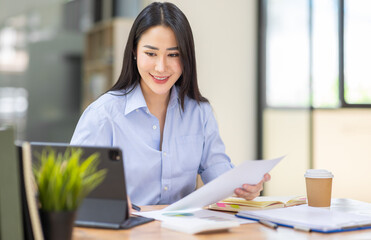 Asian Business woman using calculator and laptop for doing math finance on an office desk, tax, report, accounting, statistics, and analytical research concept
