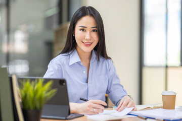 Asian Business woman using calculator and laptop for doing math finance on an office desk, tax, report, accounting, statistics, and analytical research concept
