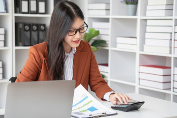 businesswoman working in the office Using calculator to calculate financial reports. Sales data with laptop computer and business documents on office table. Close up. Business finance and investment.