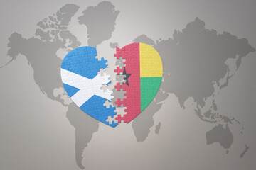 puzzle heart with the national flag of guinea bissau and scotland on a world map background.Concept.