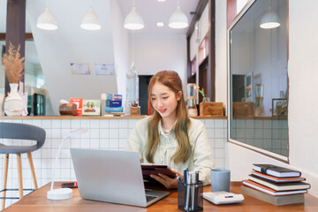Coworking space office concept, Woman entrepreneur looks data on laptop and writes data in document