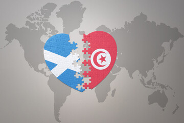 puzzle heart with the national flag of tunisia and scotland on a world map background.Concept.