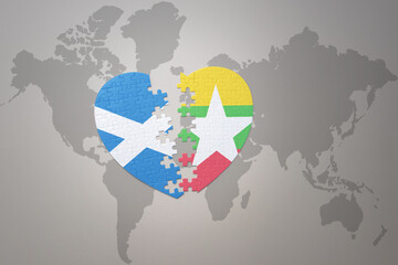 puzzle heart with the national flag of myanmar and scotland on a world map background.Concept.