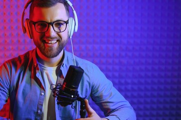 Male radio host with headphones on head and mic in studio reading news or broadcast show, toned