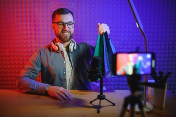 Joyful young man recording unboxing video in studio
