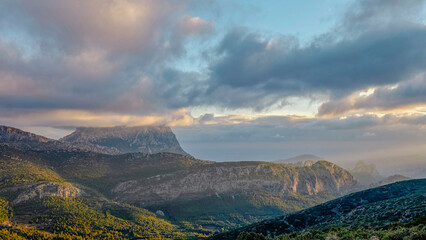 Mountains and a beautiful sky with rays of sun over the mountain Puig Campana. Mount Castellet on the right. In the Valencian Community, Alicante, Spain