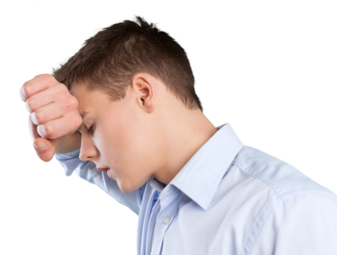 Depressed young man with fist clenched leaning his head against a wall