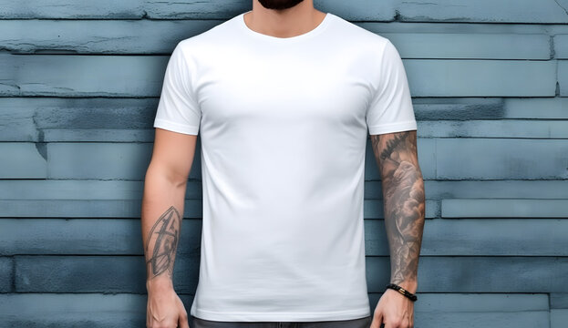 man with tattoos on arms wearing a white t shirt standing in front of a wooden wall