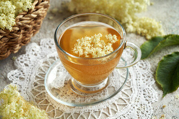 Fresh elderberry flowers in a cup of tea on a table