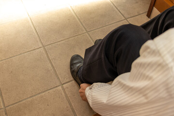 玄関で靴を履く男性

