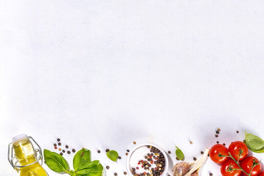 White Cooking Background With Useful Cooking Italian Mediterranean Ingredients - Tomatoes, Basil Leaves, Greens, Olive Oil, Salt, Pepper, Garlic, Flat Lay White Table Top View Copy Space 