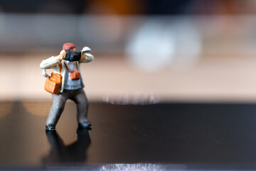 Miniature people Photography holding a camera and copy space for text , World photography day concept