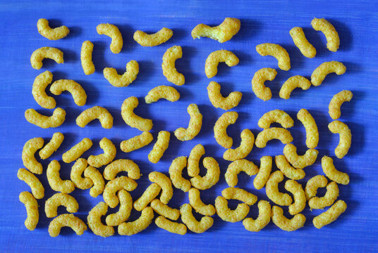 peanut curls, peanut puffs, peanut flavoured wotsits, delicious snacks, flat lay on blue background