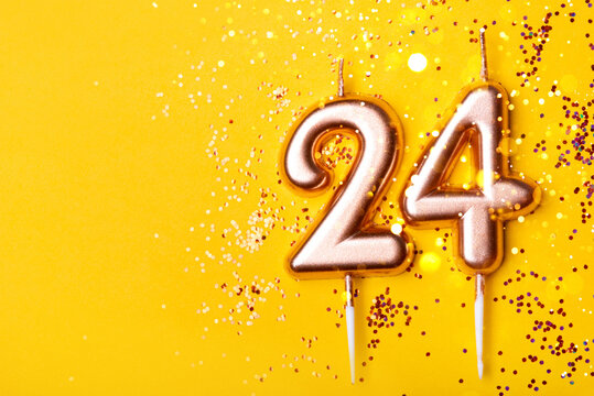 24 years celebration. Greeting banner. Gold candles in the form of number twenty four on yellow background with confetti.