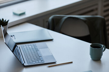 Closeup of open laptop on desk at empty office workplace, copy space