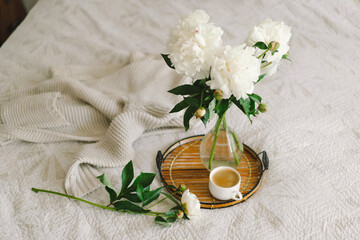 Still life details in home interior of living room. Cup coffee and bouquet white white peonies flowers. Cozy home