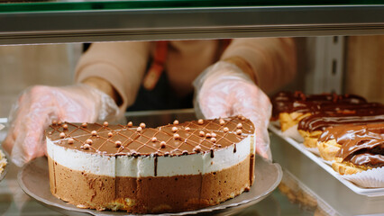 In the bakery cafe closeup to the camera capturing video of a salesman arrange carefully chocolate cake from the showcase fridge