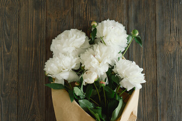 Bouquet of beautiful white peonies on wood background. Stylish floral greetings. Mothers day