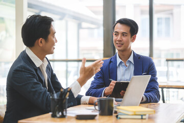 Two young business people sitting in modern office and discussing project strategy together.