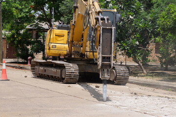 Road drilling vehicle, backhoe, yellow, attached to the drilling head, the Yak head, working