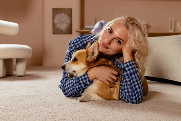 Attractive blonde hair girl and a Welsh corgi Pembroke dog cuddling together.