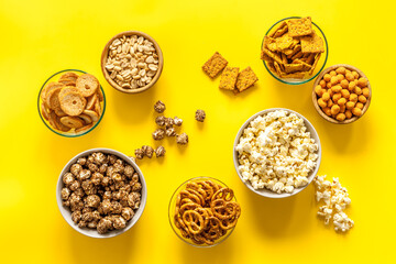 Set of many salty snacks in bowls - pretzels nuts chips top view