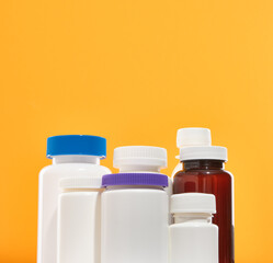 Medical jars with pills of different shapes and sizes on a yellow background. Assorted pharmaceutical medicine pills, tablets and capsules.