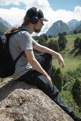 Naklejka premium Young man in summer mountains at sunset and enjoying view of nature. Happy hiker, life goal, success, freedom and happiness.