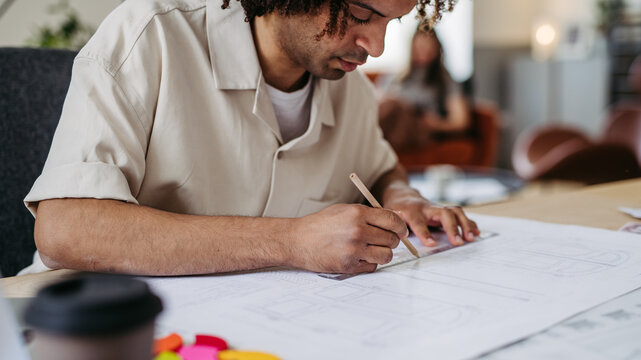 Young multiracial man drawing something in designers studio.