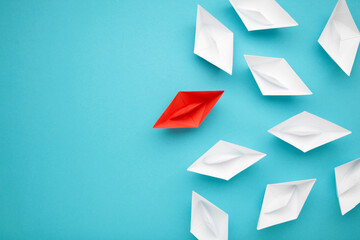 Leadership concept. Red leader paper ship leading among white on blue background.