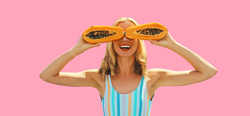 Summer portrait of happy cheerful laughing young woman posing with juicy papaya fruit on pink...